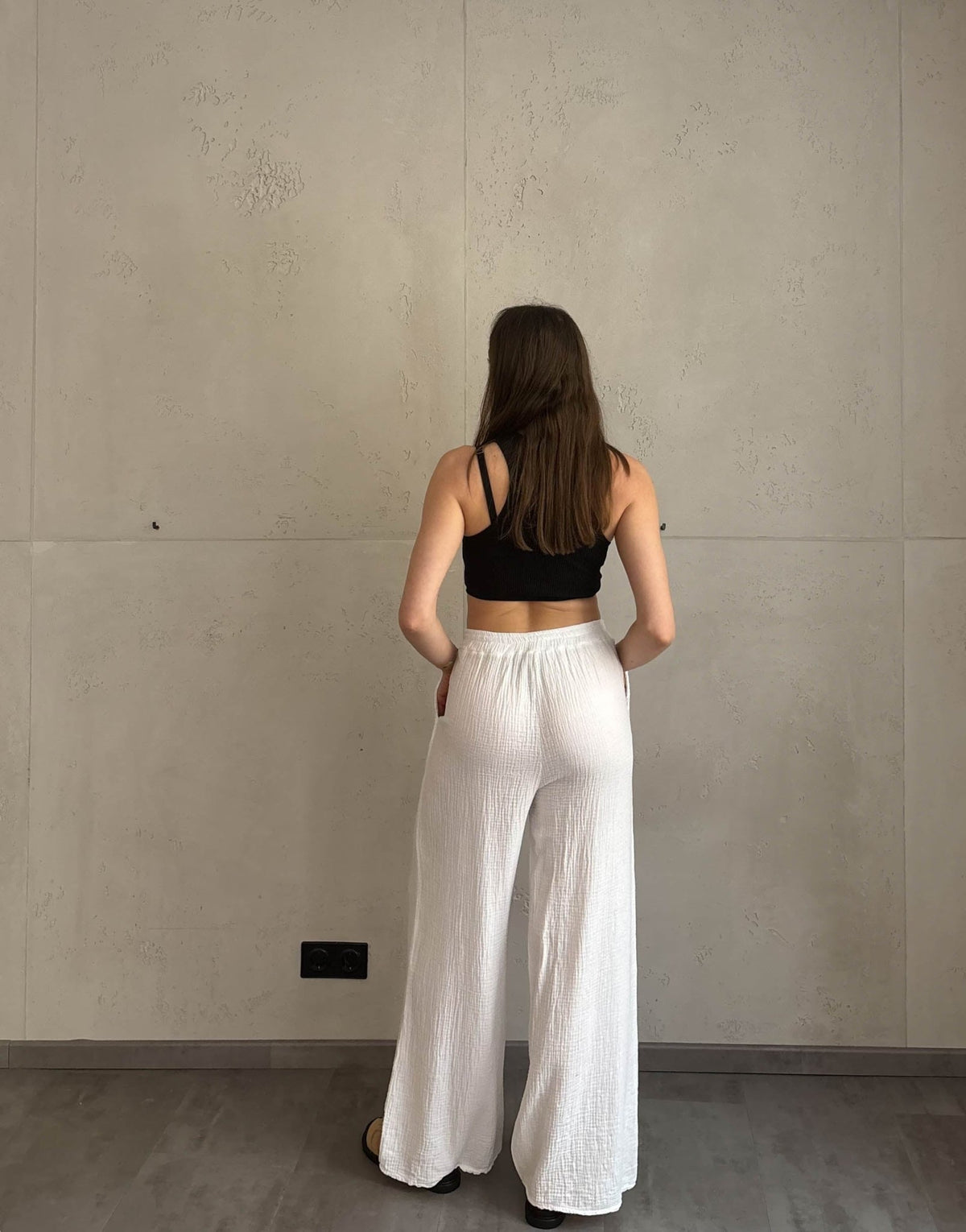 Frau mit brauen Haaren trägt klassische Musselinhose in weiß
